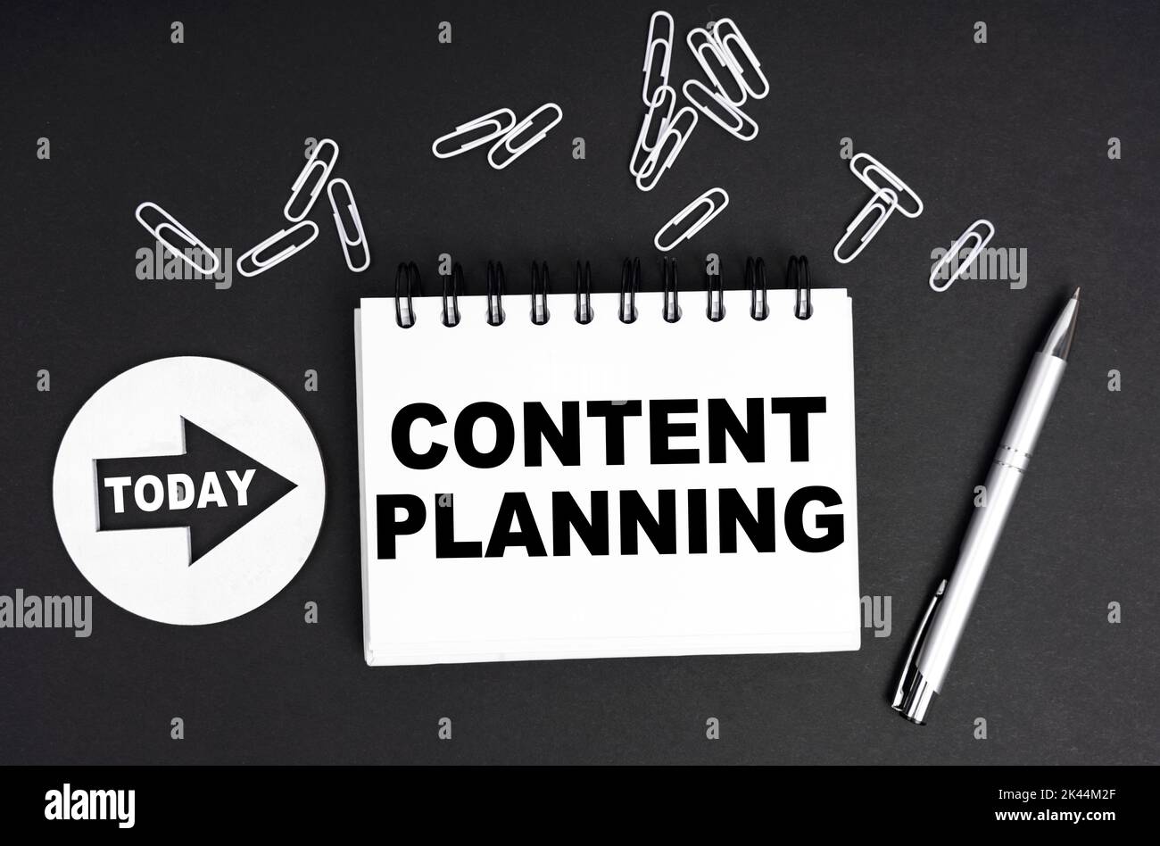 Concetto aziendale. Su sfondo nero, un piatto rotondo - oggi e un quaderno con l'iscrizione - Content Planning Foto Stock
