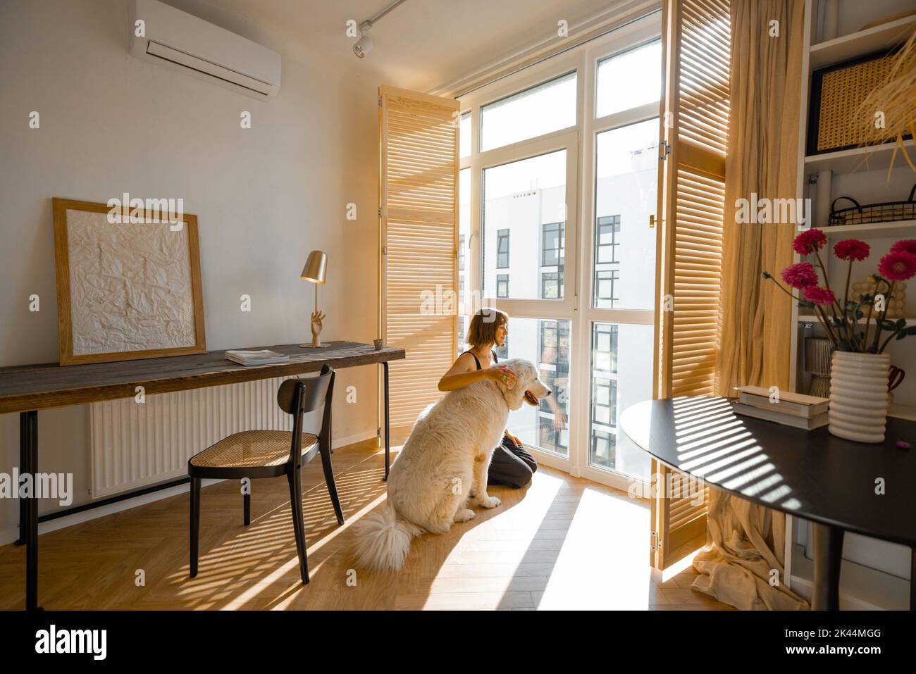 Donna si alza con il cane vicino alla finestra tende a casa Foto Stock