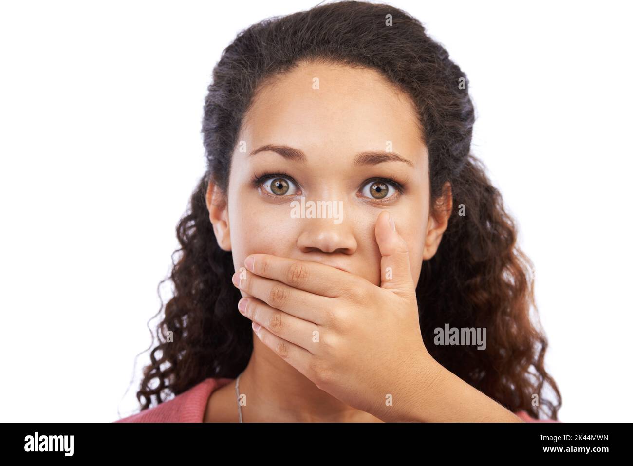 Stordito nel silenzio. Una bella giovane donna coprendo la bocca con le mani e guardando scioccato su uno sfondo bianco. Foto Stock