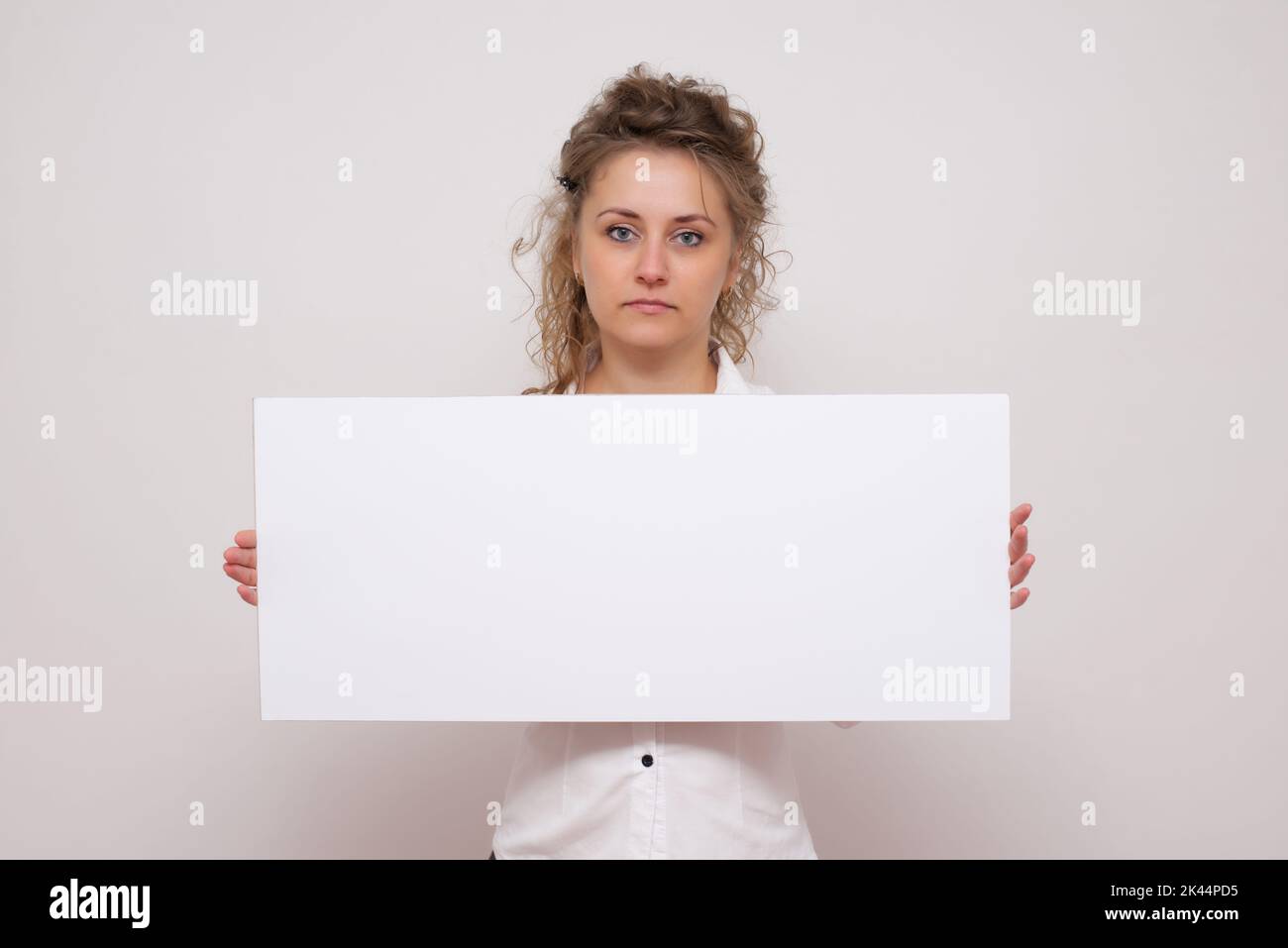 Bella donna che posa dietro un pannello bianco isolato su sfondo bianco foto stock Foto Stock