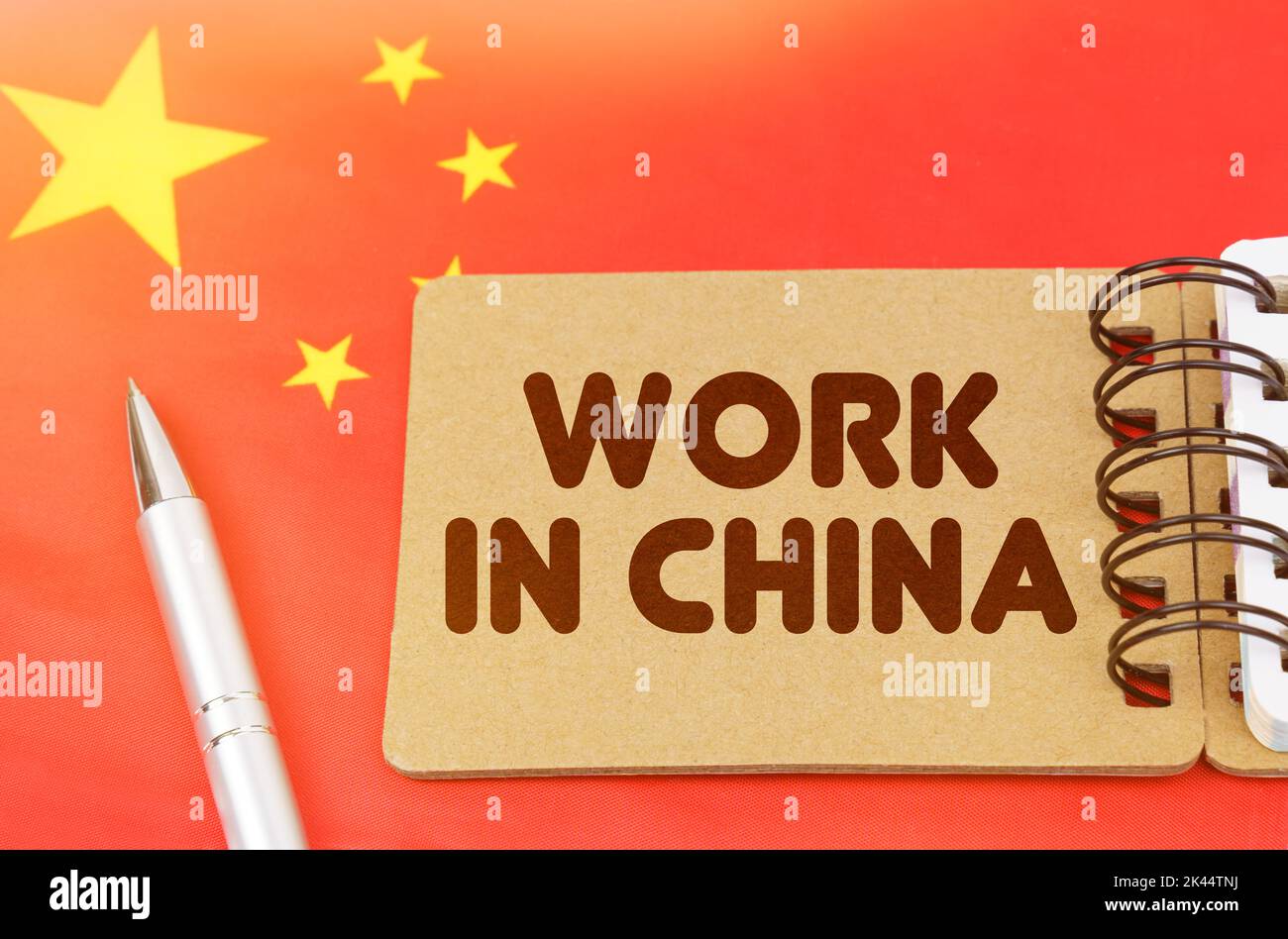 Concetto di economia nazionale. Sulla bandiera della Cina si trova un taccuino con l'iscrizione - lavoro in Cina Foto Stock