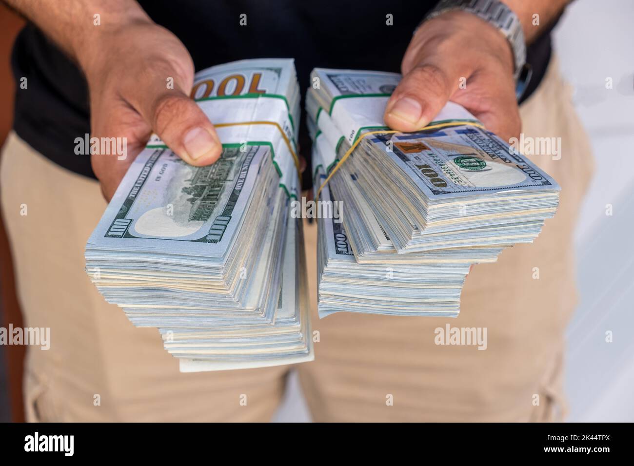Pacchetti di dollari americani nelle mani di un uomo d’affari. Messa a fuoco selettiva Foto Stock