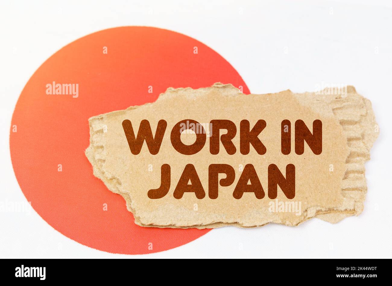 Concetto di economia nazionale. Sulla bandiera del Giappone si trova un taccuino con l'iscrizione - lavoro in Giappone Foto Stock