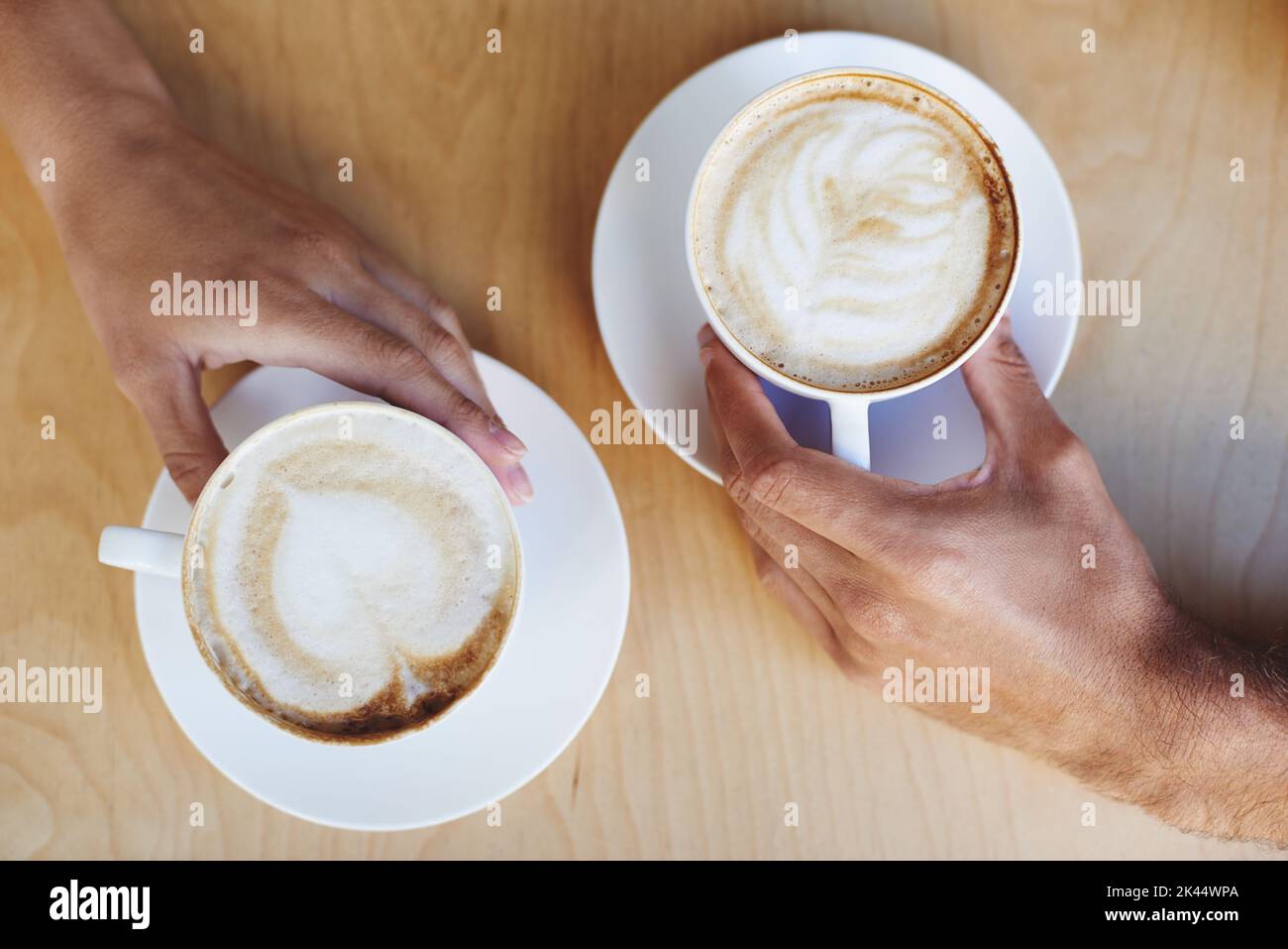 Caffè. Immagine ritagliata di due mani di persone che tengono cappuccini. Foto Stock