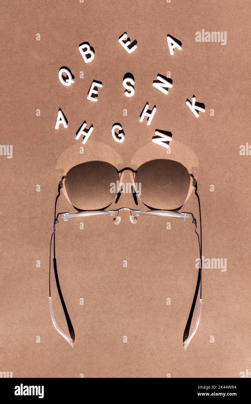 Lettere bianche in occhiali a fuoco su sfondo marrone. Concetto di visione. Foto Stock