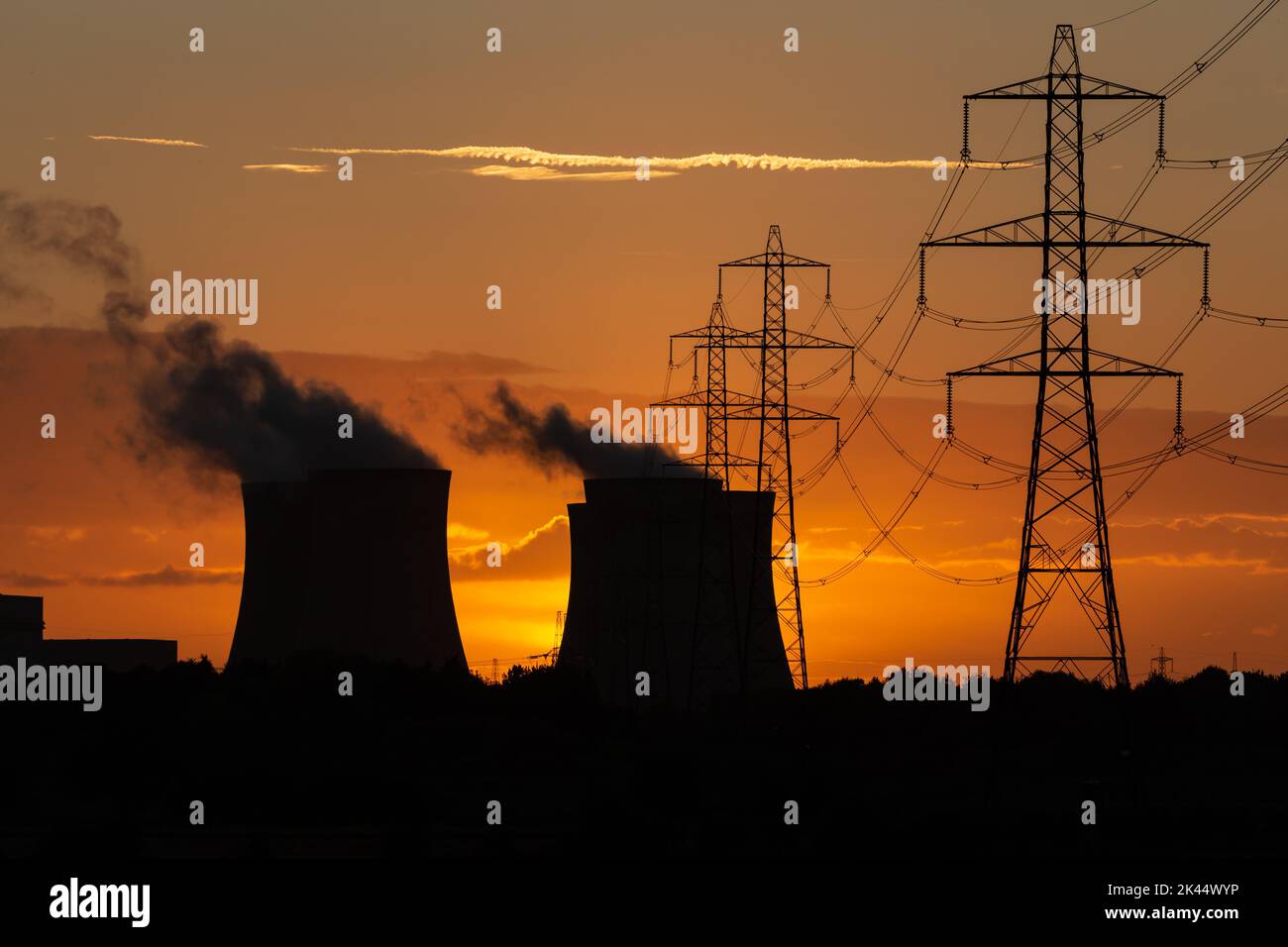 Silhouette delle torri di raffreddamento di una centrale elettrica contro un bellissimo tramonto autunnale vicino a Drax nel North Yorkshire, Regno Unito, con piloni elettrici e plumes Foto Stock