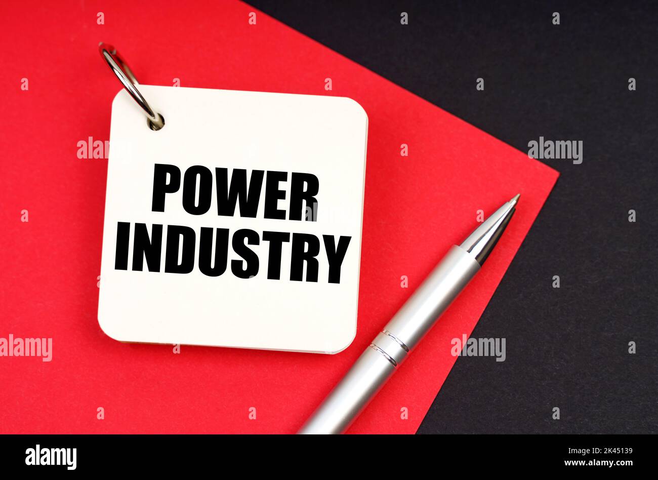 Concetto industriale e commerciale. Su uno sfondo nero e rosso si trovano una penna e un notebook con l'iscrizione - Power Industry Foto Stock