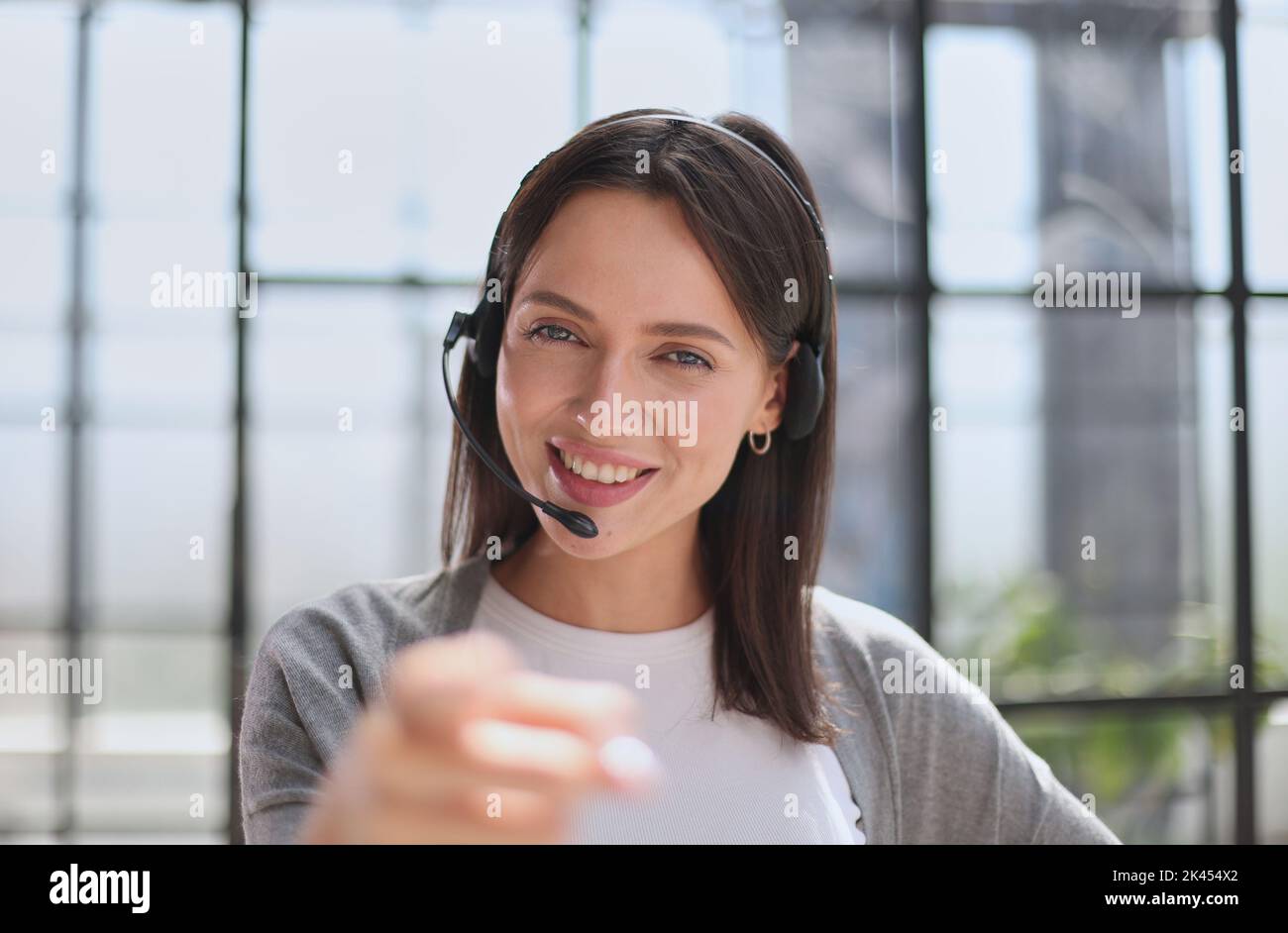 operatore del call center donna che punta con il dito verso la fotocamera e verso di te, segnale di mano, gesto positivo e sicuro dalla parte anteriore Foto Stock