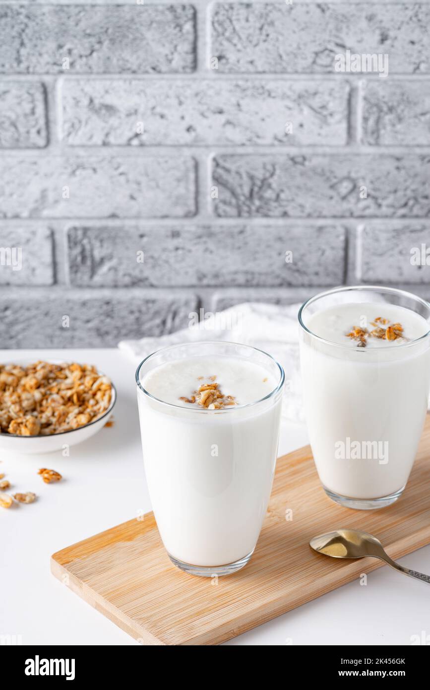 Kefir, latticello o yogurt al granola. Yogurt in vetro su sfondo chiaro. Foto Stock