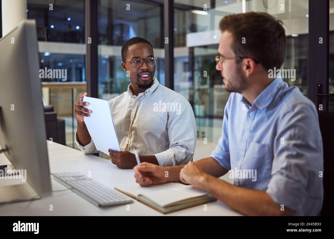 Uomini d'affari, computer o pianificazione in ufficio notturno con notebook, carta o documenti per la società di programmazione. Lavoro di squadra, collaborazione o conversazione Foto Stock