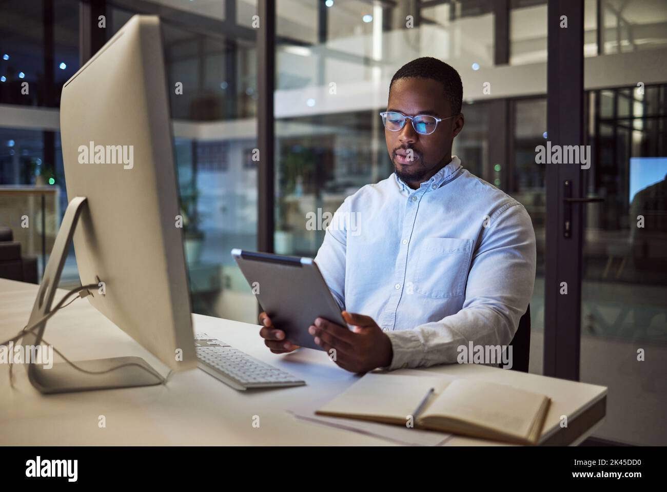 Uomo d'affari nero, pianificazione tablet e desktop di notte all'avvio per idee online, strategia e app di connessione sulla tecnologia 5g in Nigeria. Dipendente Foto Stock