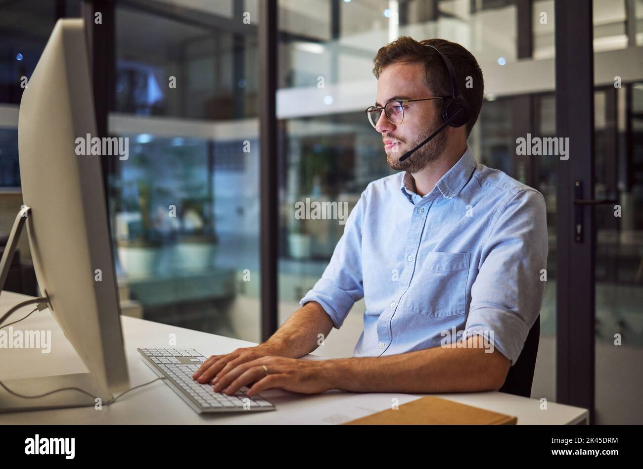Call center, comunicazione web e uomo d'affari che lavora come consulente come società di telemarketing in ufficio buio. Consulenza di un addetto all'assistenza clienti su Foto Stock