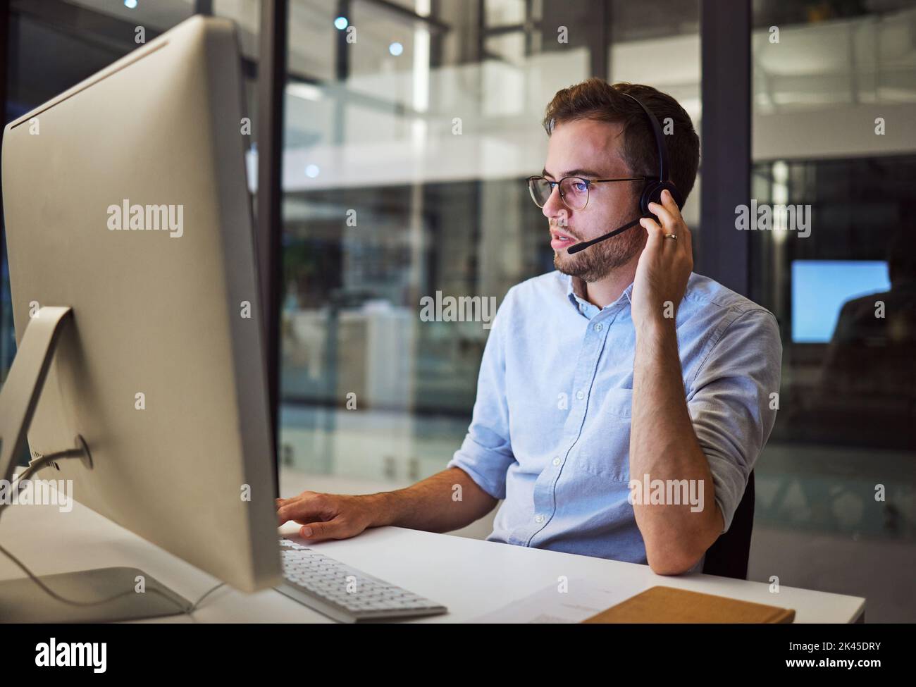 Telemarketing, uomo e dipendente nel call center con cuffie alla scrivania. Lavoratore o consulente al tavolo sul computer che parla con il cliente, controllo Foto Stock