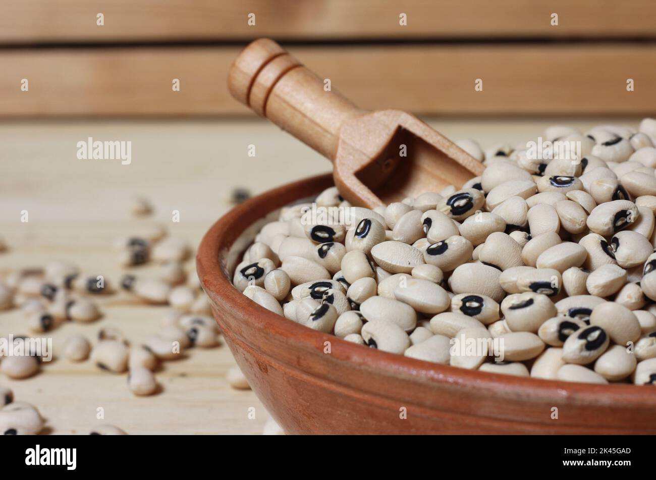 Piselli secchi neri secchi non cotti in ciotola su tavola di legno Foto Stock