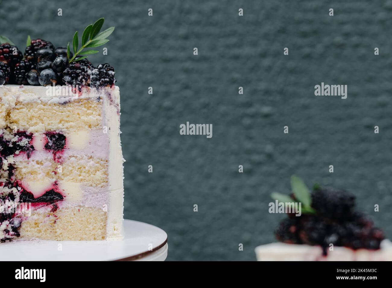 Metà di un primo piano di torta al cioccolato con frutti di bosco su sfondo grigio Foto Stock