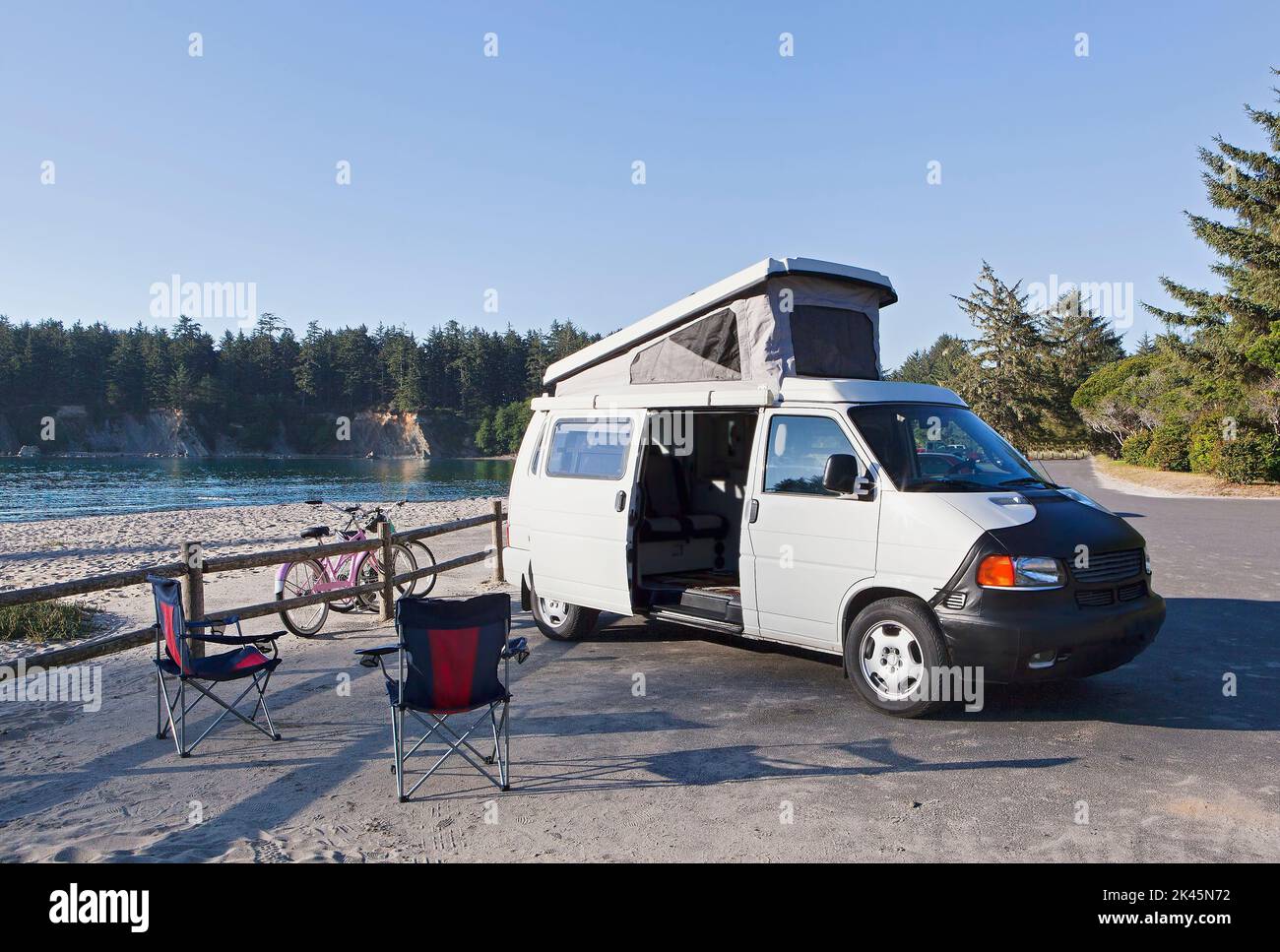 Un camper parcheggiato in una baia a Cape Arago sulla costa dell'Oregon., sedie da campeggio e biciclette. Foto Stock