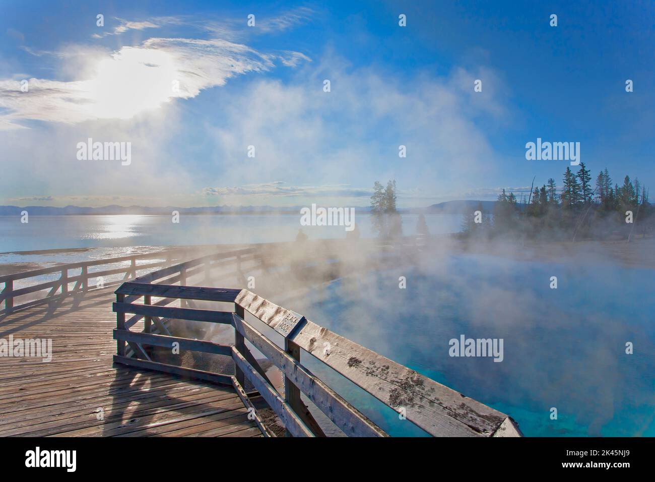 Una passeggiata sull'acqua, il vapore che sale, le persone sullo sfondo e la vista su un lago fino alle montagne, nel Wyoming. Foto Stock