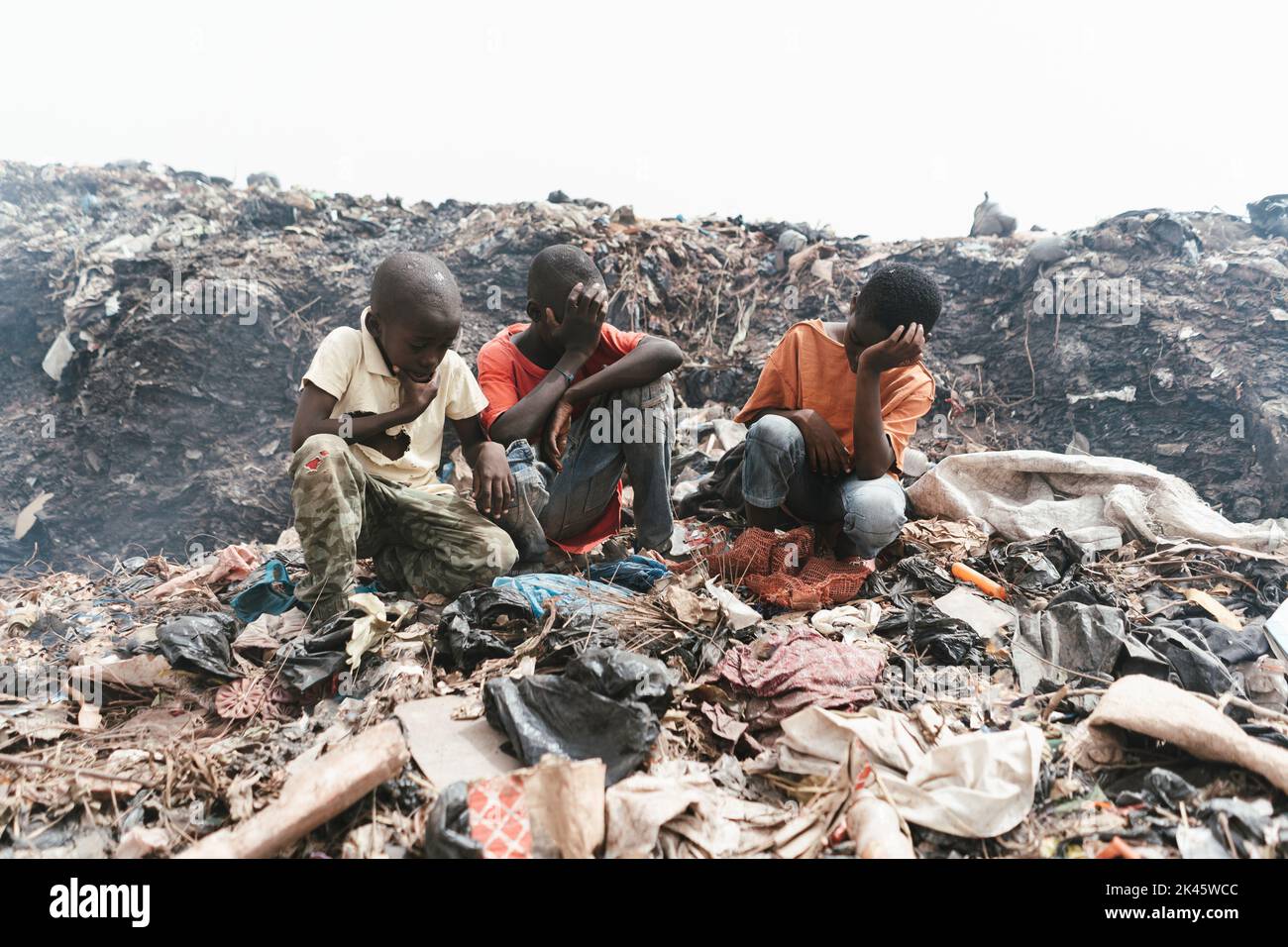 Tre ragazzi africani seduti con un volto triste in una discarica fuori Bamako, Mali Foto Stock