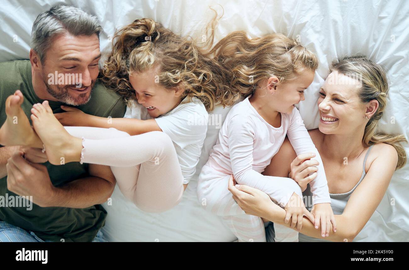 Felice, famiglia e bambini con un sorriso in una camera da letto casa letto trascorrere il tempo di qualità insieme. Bambina bambini, madre e uomo in una casa con Foto Stock