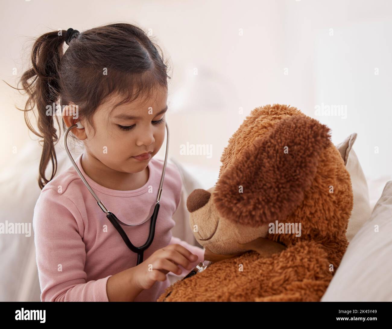 Stetoscopio, ragazza e un orsacchiotto giocando futuro gioco medico mostrando la cura su un buon controllo di assicurazione sanitaria. Piccolo bambino cute che ascolta o che controlla Foto Stock