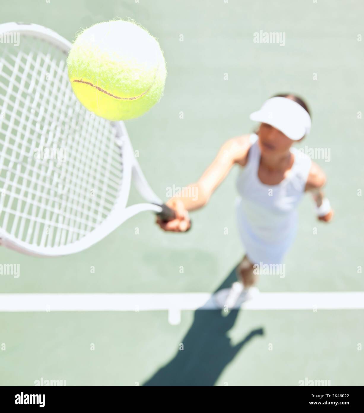 Donna tennis sul campo da tennis con una palla da tennis in aria. Primo piano di una giovane atleta che colpisce la palla con una racchetta da tennis per servire durante un Foto Stock