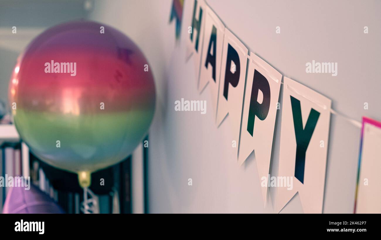 Buon compleanno nastro dettaglio con un grande decorazione palloncino su una parete grigio blu Foto Stock