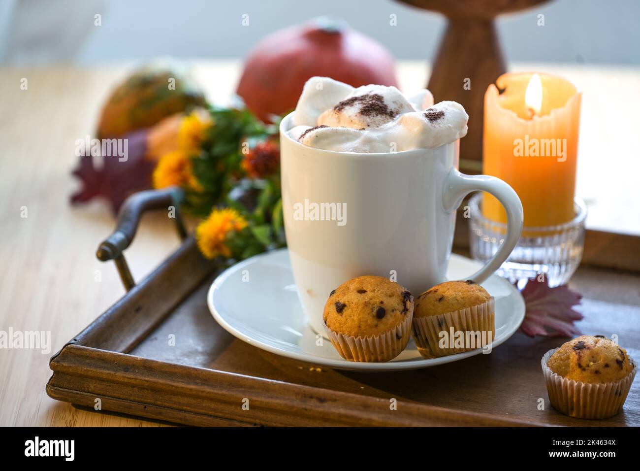 Tazza bianca con bevanda calda al cioccolato e marshmallow in fusione, muffin, candela e decorazione autunnale su un tavolo, spazio copia, focus selezionato, profondità stretta Foto Stock