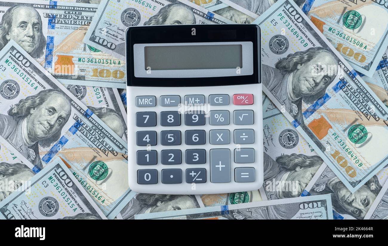 calcolatrice sullo sfondo di banconote in dollari. Denaro dollari e calcolatrice, concetto di economia, distribuzione di denaro. Crowdfunding. Business e financ Foto Stock