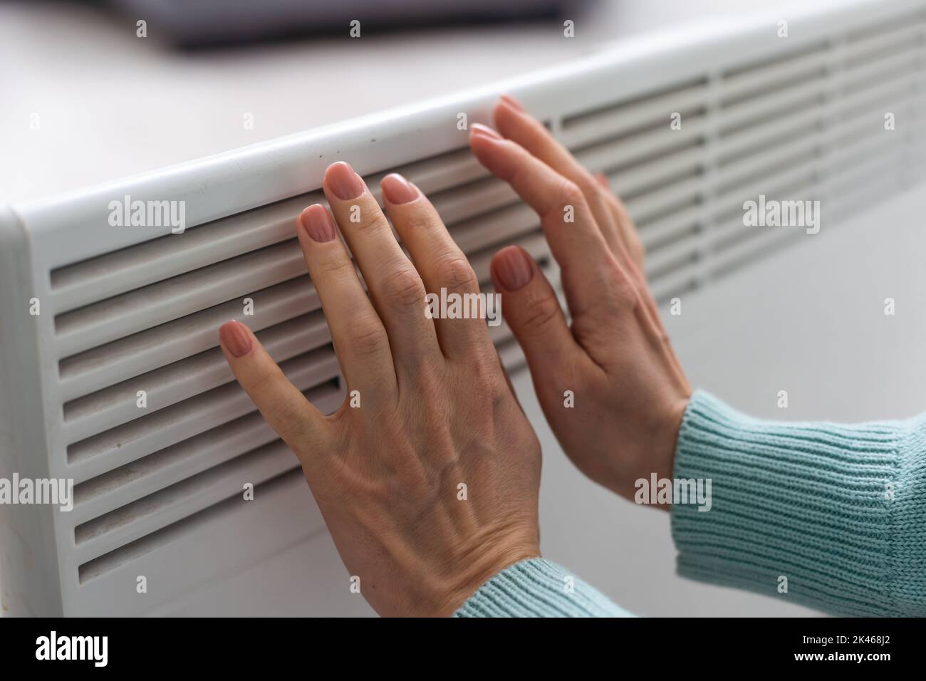 Mano della donna su un radiatore bianco. Stagione di riscaldamento. Crisi energetica. Batterie fredde. Riscaldamento centralizzato Foto Stock
