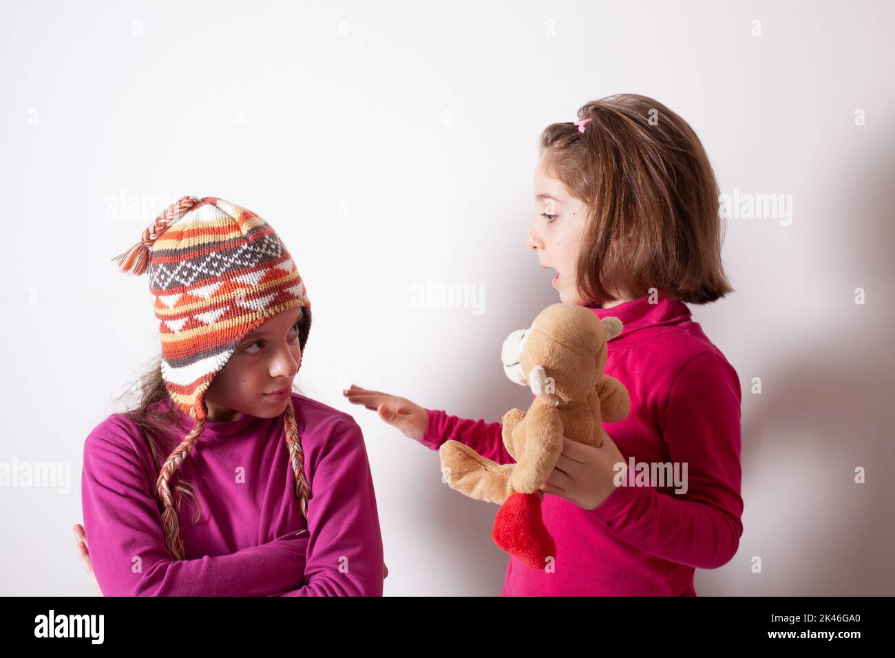 Concetto avido dei bambini. Suore relazioni questioni. Condividi i giocattoli con gli amici. I bambini su sfondo bianco giocano con i giocattoli Foto Stock