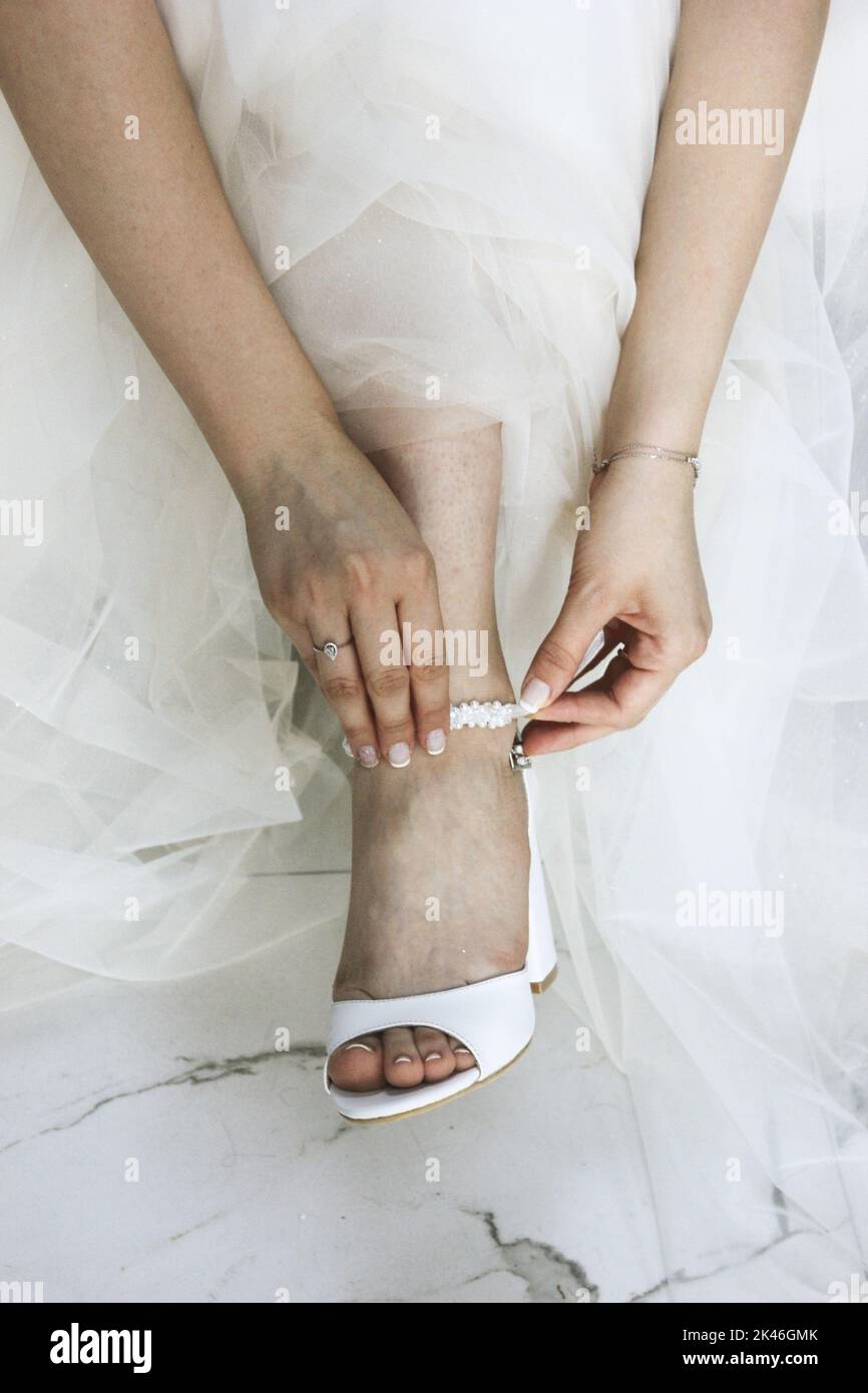 Sposa in abito da sposa mettendo su scarpe da sposa, sposa sempre pronto per il matrimonio, concetto di moda Foto Stock