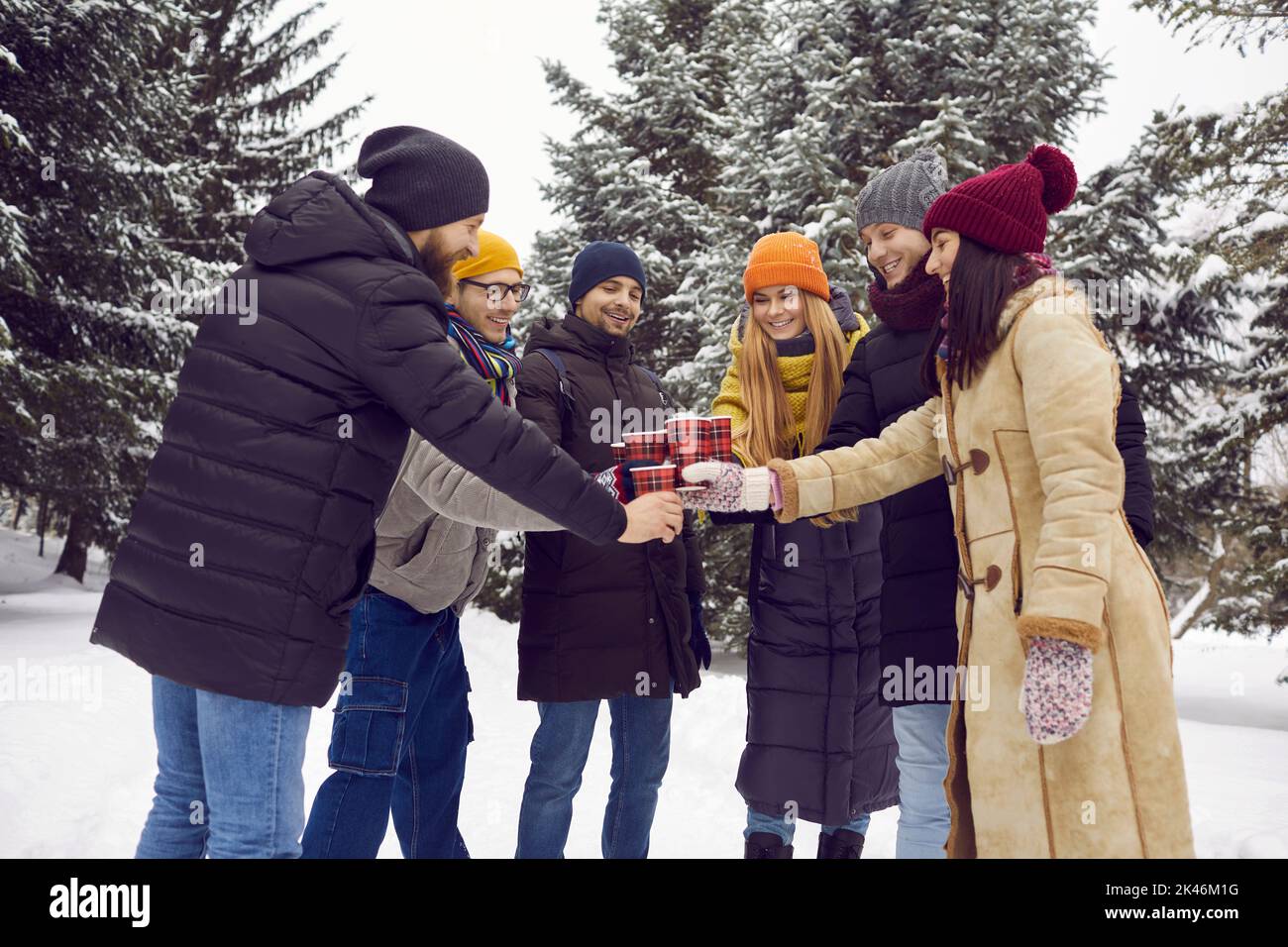 Gruppo di giovani amici felici divertirsi all'aperto e bere caffè nel parco invernale Foto Stock