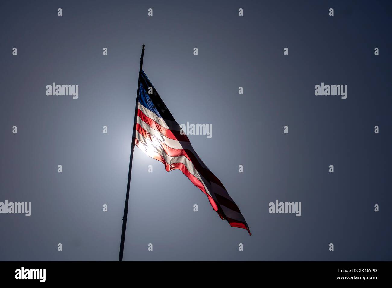 Il sole ha retroilluminato le stelle americane e la bandiera a strisce che soffia nel vento in una giornata intensa Foto Stock