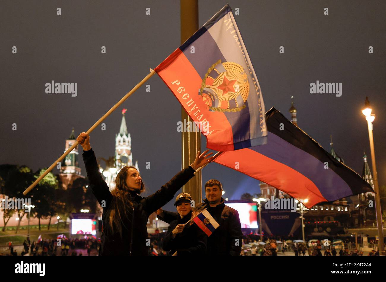 Le persone detengono bandiere delle autoproclamate Repubbliche di Donetsk e Lugansk mentre gli spettatori si riuniscono davanti agli schermi per assistere a un concerto che segna l'annessione dichiarata dei territori controllati dalla Russia di quattro regioni ucraine di Donetsk, Luhansk, Kherson e Zaporizhzhia; Dopo aver indetto quello che le autorità russe hanno chiamato referendum nelle aree occupate dell'Ucraina, condannate da Kyiv e dai governi di tutto il mondo, vicino alla Piazza Rossa nel centro di Mosca, Russia, 30 settembre 2022. FOTOGRAFO REUTERS/REUTERS Foto Stock