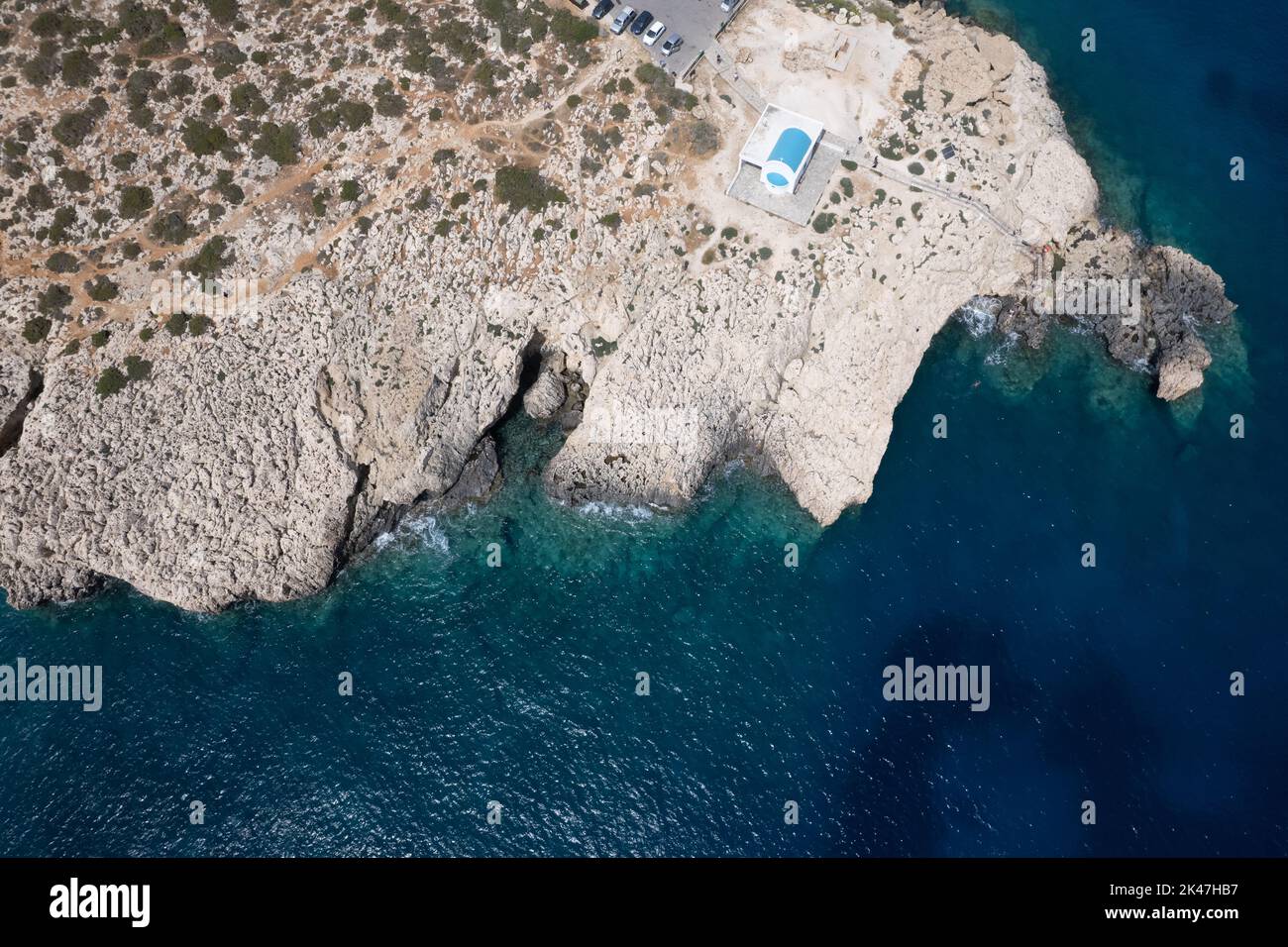 Fotografia aerea del drone della penisola di Capo Greco con la chiesa di Agioi Anargyroi sulle rocce. Acque turchesi dell'oceano Foto Stock
