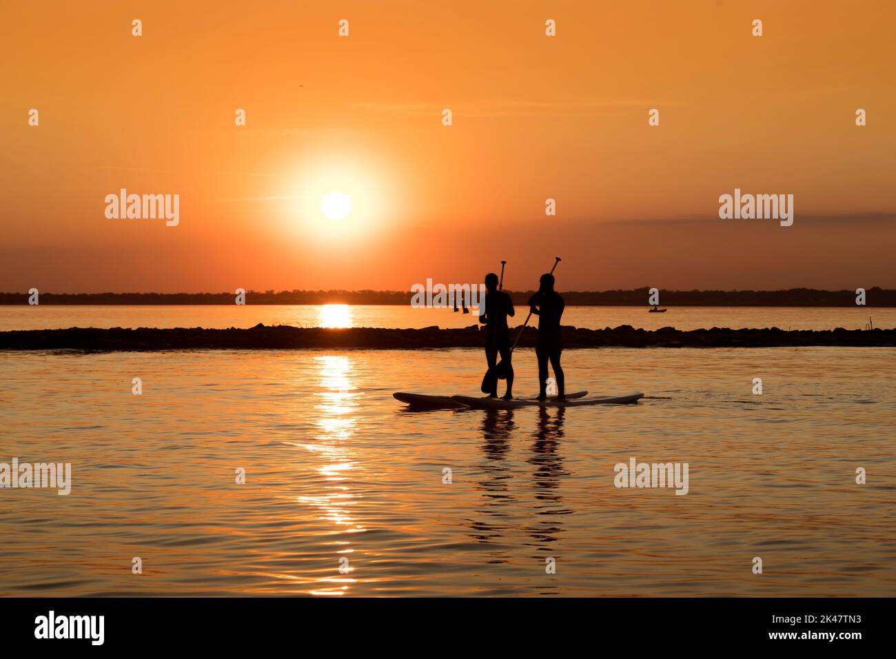 Silhouette di un uomo con una pagaia su una tavola da surf SUP al tramonto di Odessa. Pittoresco corpo d'acqua la sera. Tema di uno stile di vita attivo Foto Stock