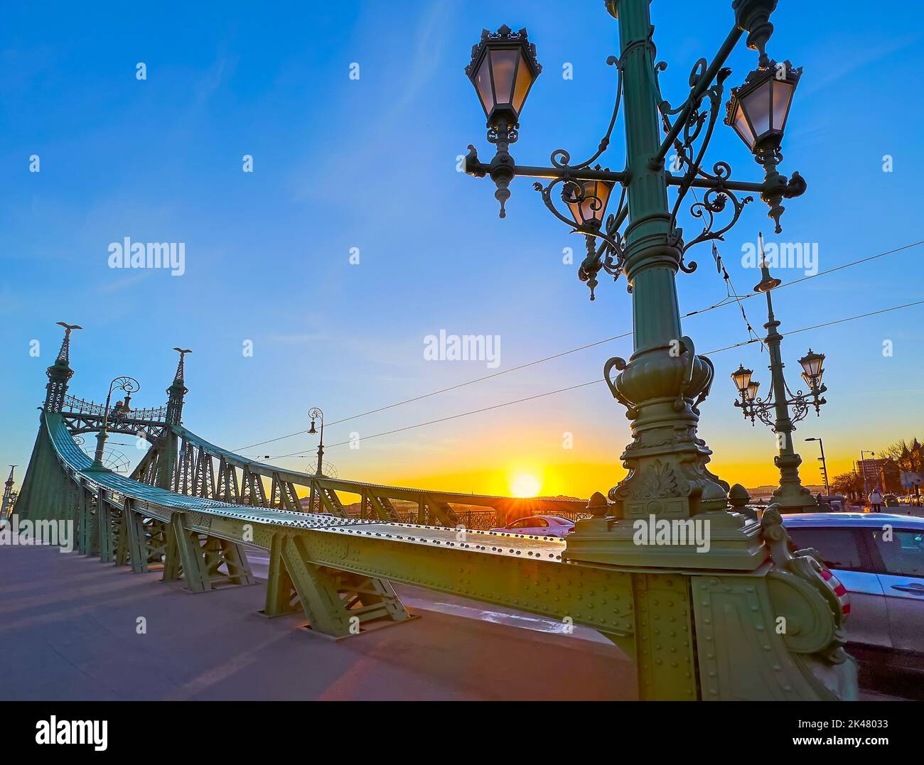 L'alba dorata dietro le verdi costruzioni dell'iconico Ponte della libertà, Budapest, Ungheria Foto Stock