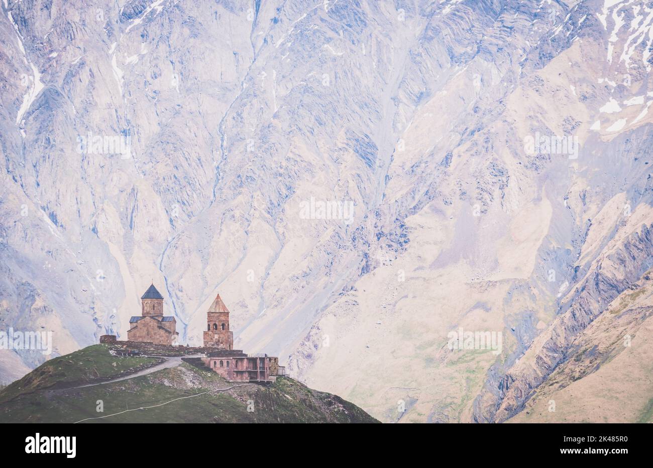 Chiesa ortodossa cristiana della trinità Gergeti del XIV secolo con drammatiche strutture montane sullo sfondo. Luoghi religiosi e storici in Caucaus.Geor Foto Stock