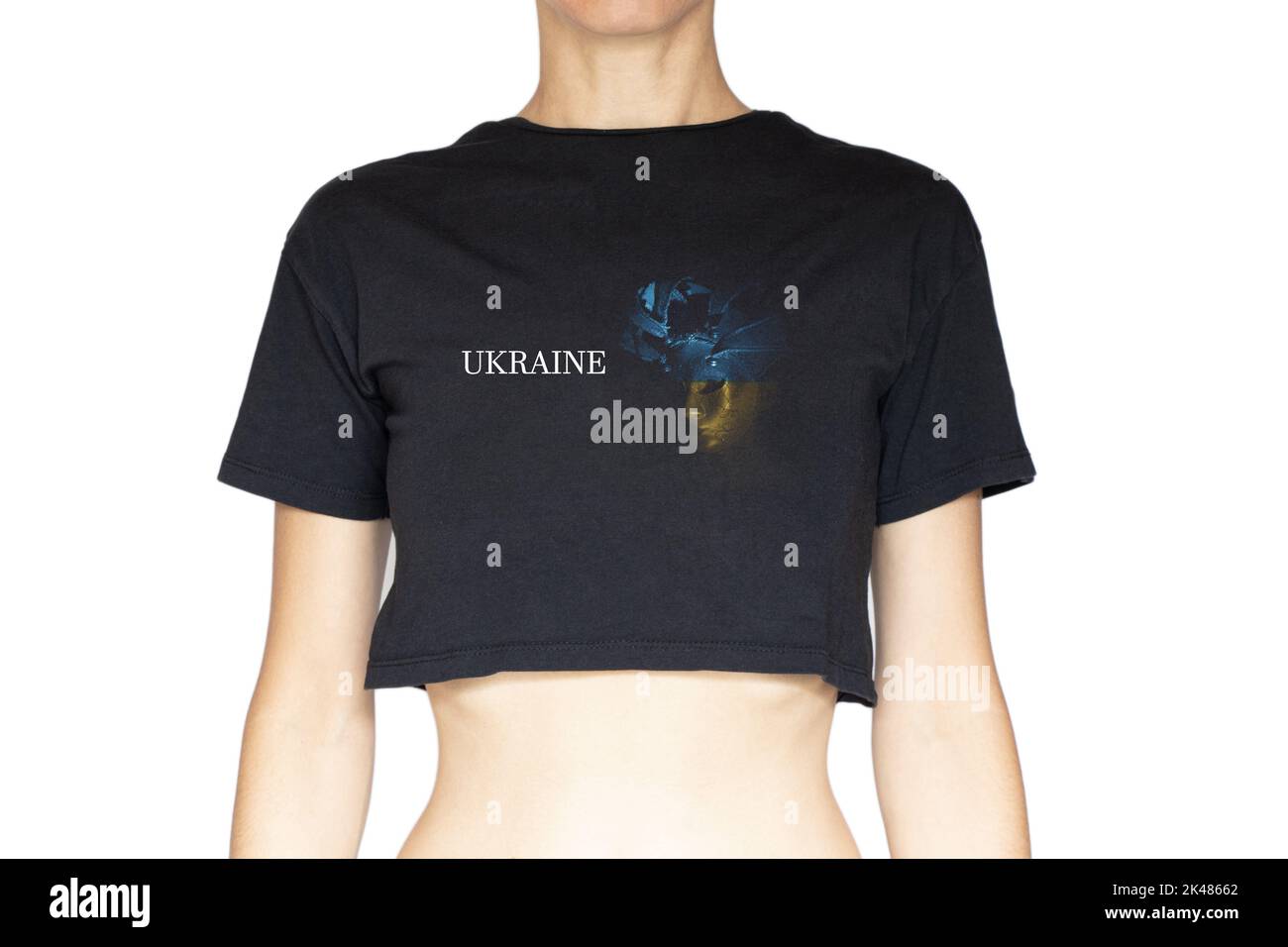 Una ragazza in una T-shirt nera e una foto sul disegno di una maschera veneziana nei colori della bandiera dell'Ucraina e il testo Ucraina su un backgroun bianco Foto Stock