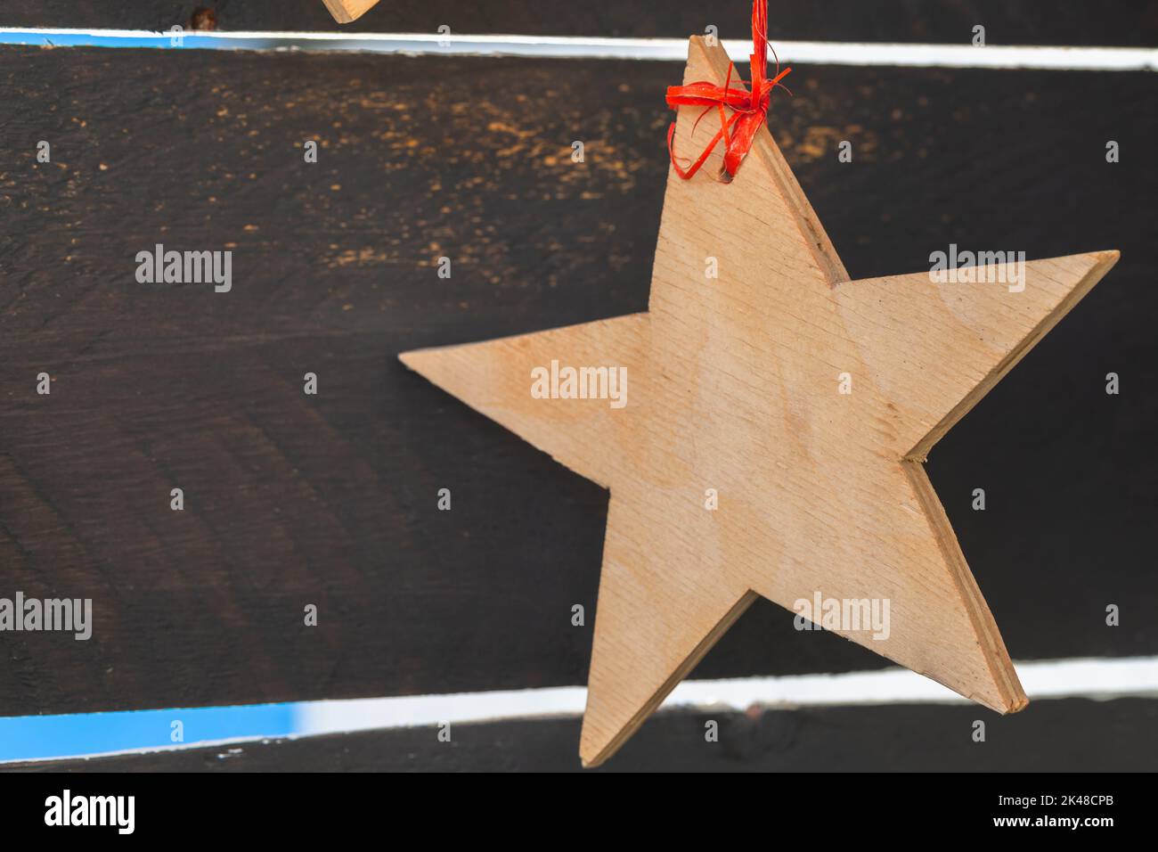 Stella di legno appesa su nastro rosso, decorazione di Natale su pareti di legno scuro Foto Stock