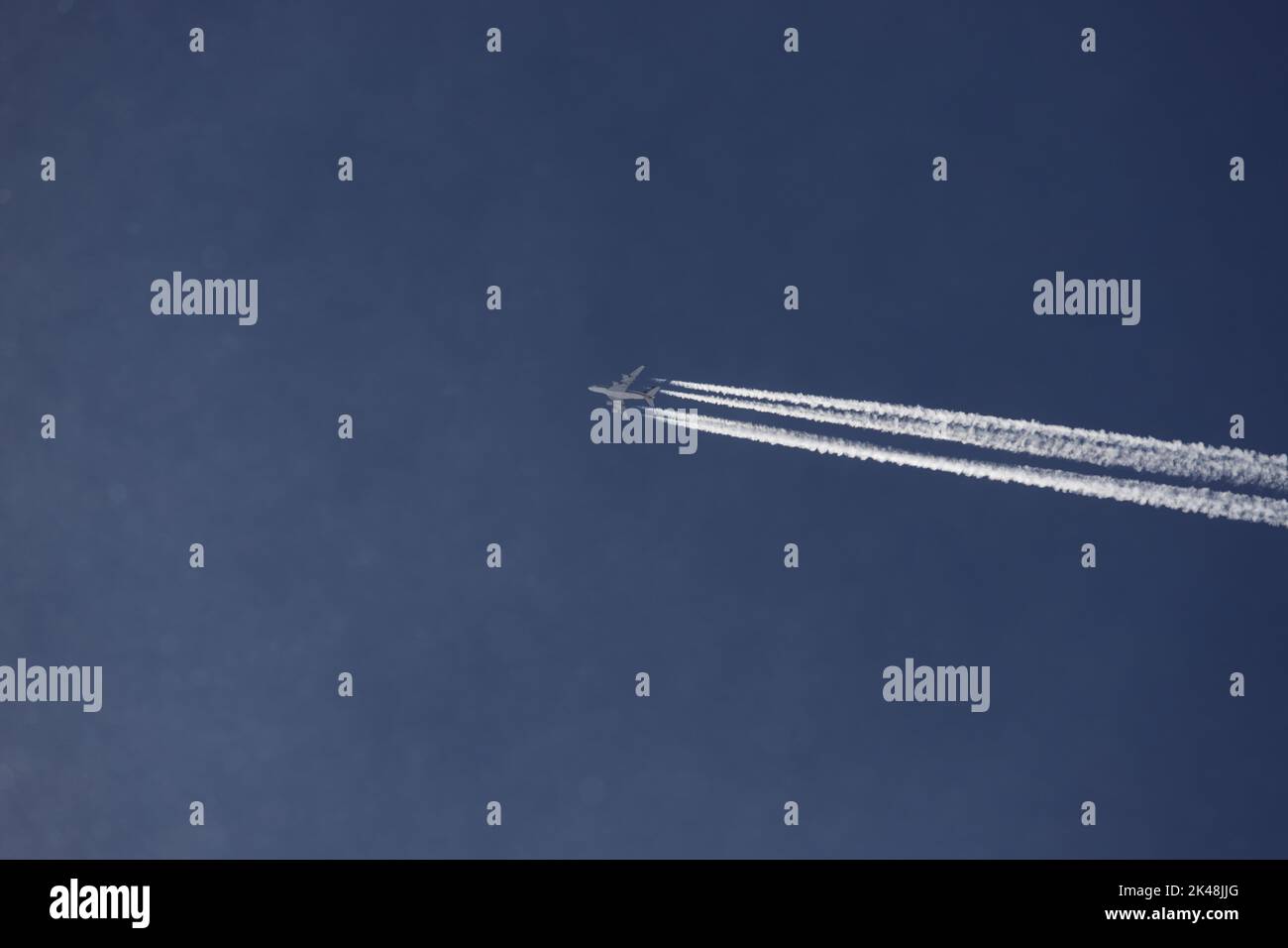VOR stahlblauem Himmel zieht ein Airbus A380 seine Bahn. Die vier Triebwerke zeichnen Kondenzstreifen den wolkenlosen Himmel. Foto Stock