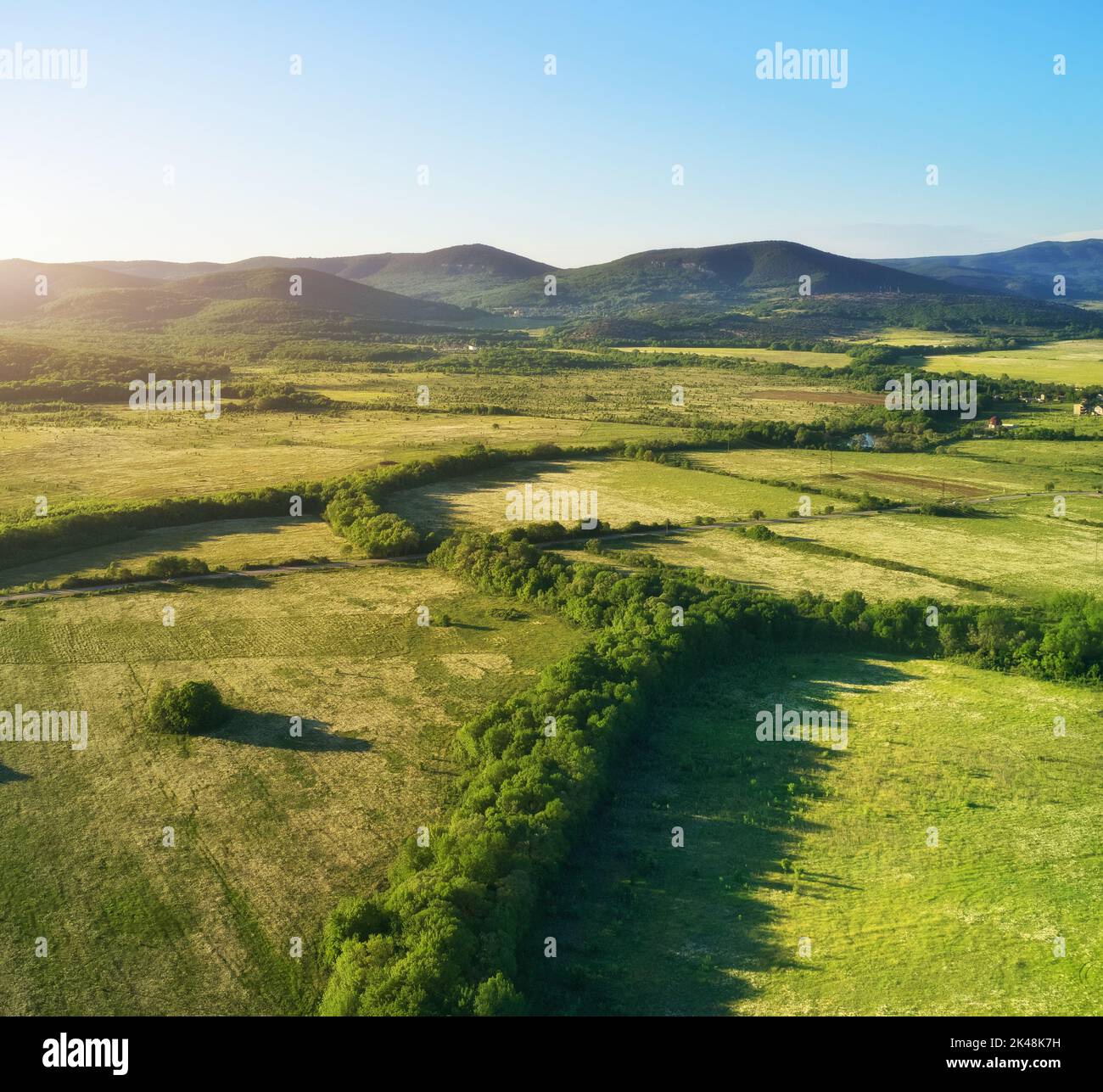 Vista panoramica aerea dello splendido paesaggio della valle e delle colline sullo sfondo e delle suggestive nuvole nel cielo. Foto Stock