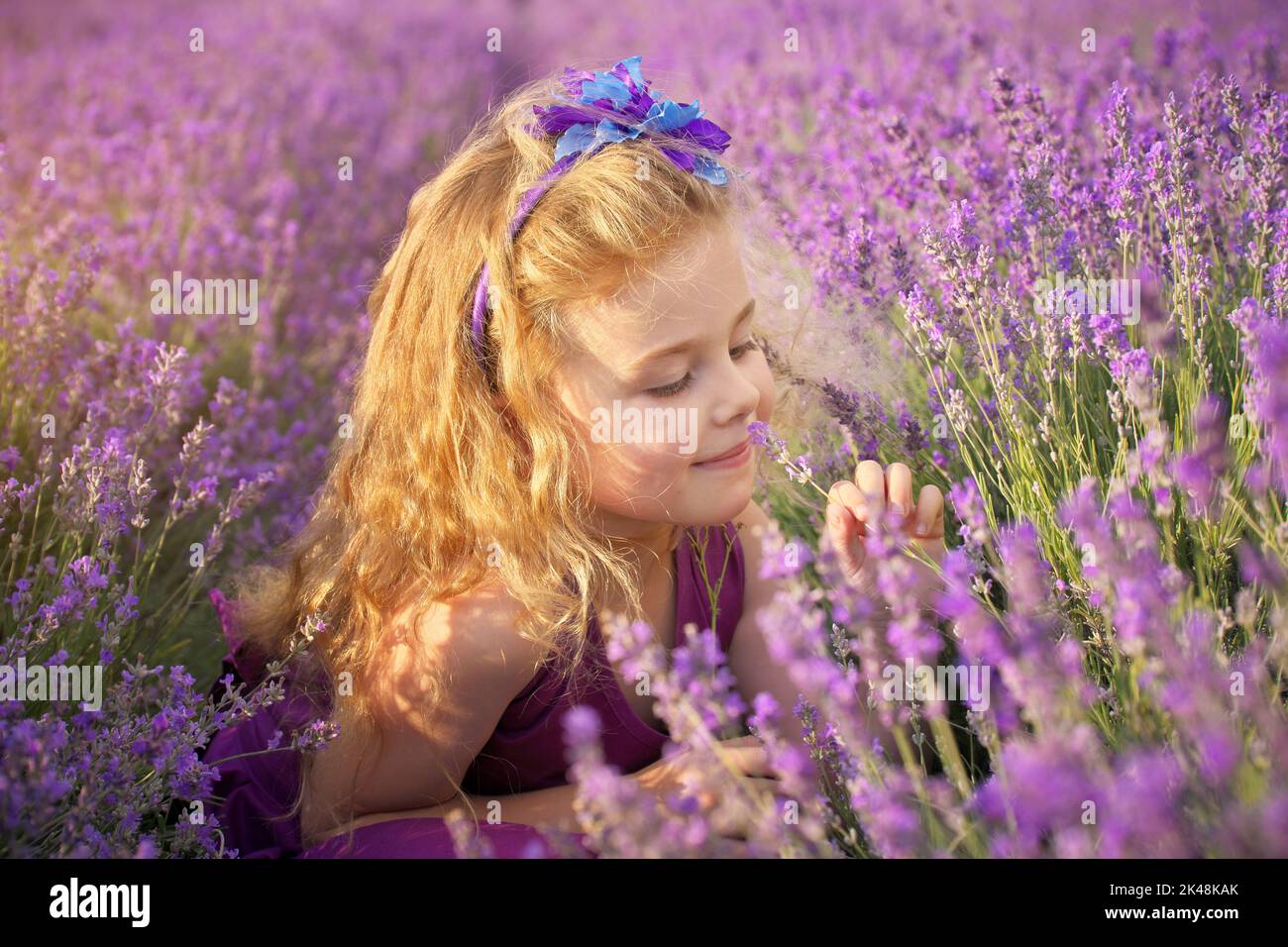 Cute bambina odore i fiori di lavanda in prato. Ritratto e composizione della natura. Foto Stock