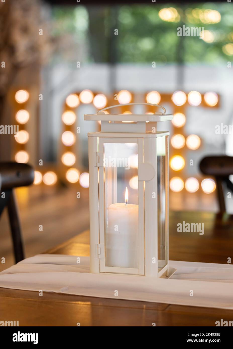 Bella cera vera candela che brucia in romantica location matrimonio con lettere d'amore illuminato fuori fuoco dietro. Foto Stock