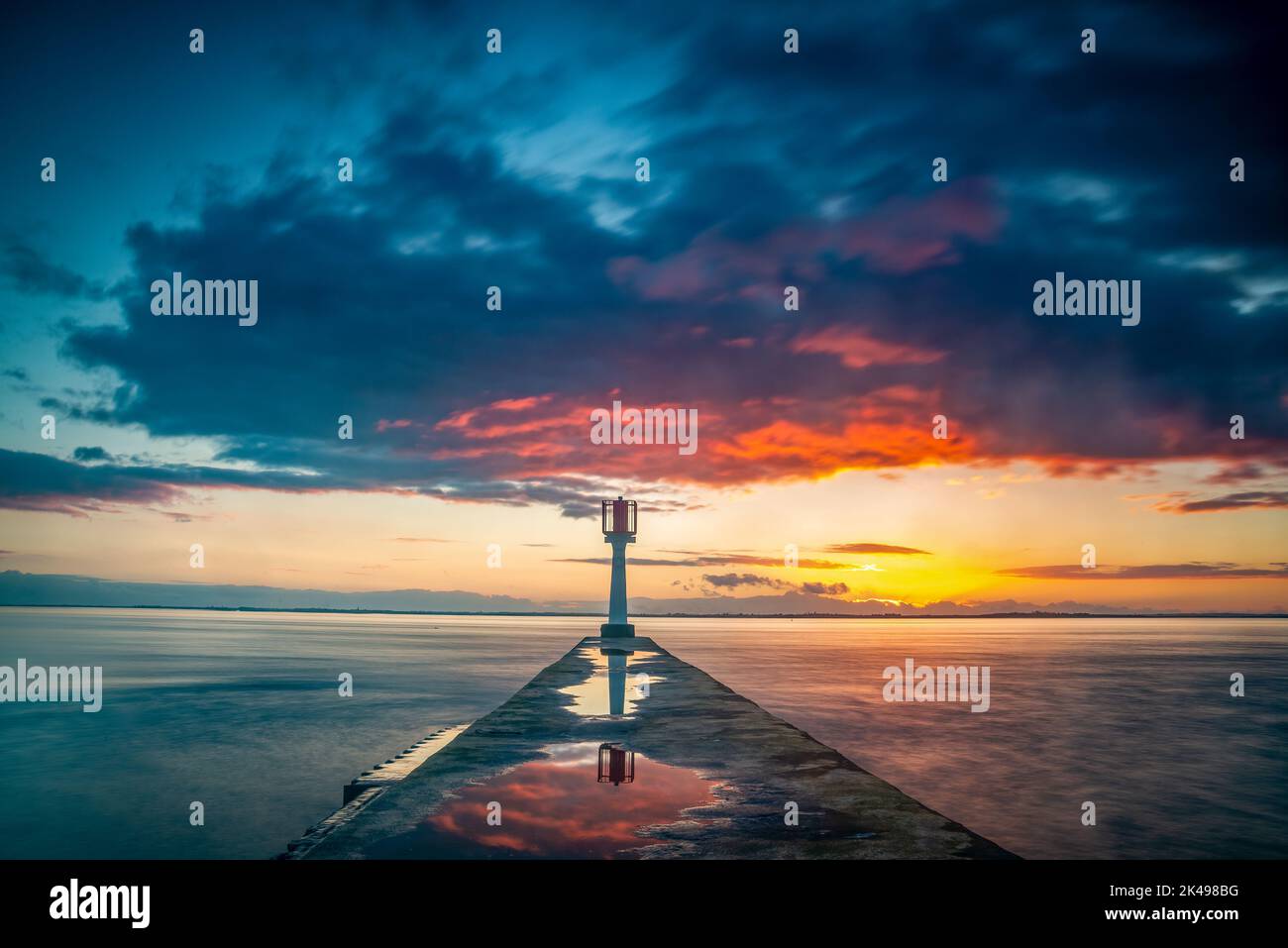 Tramonto drammatico con faro e molo sulla costa occidentale dell'oceano Atlantico dell'estuario della Gironda, Charente Maritime, Francia Foto Stock