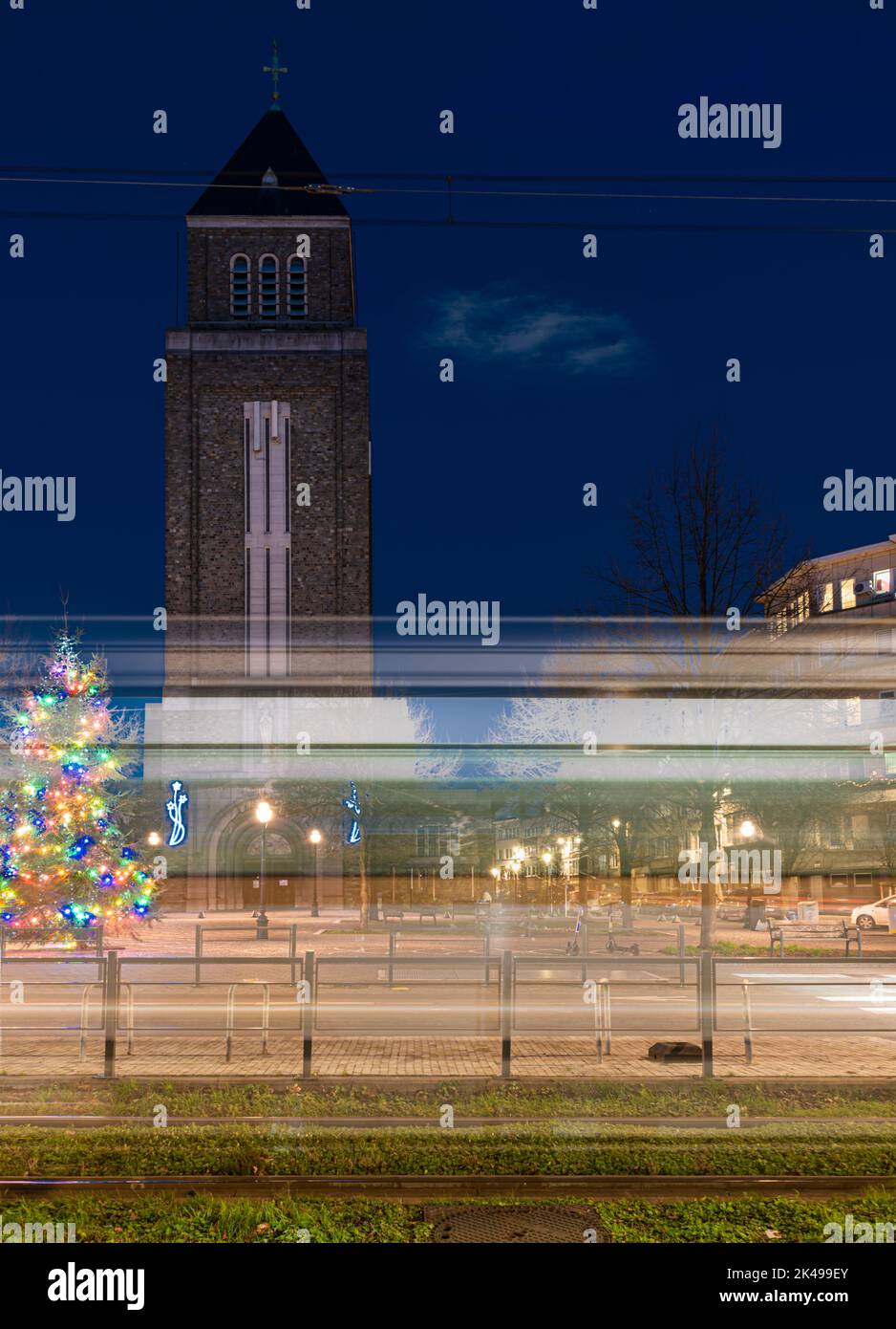 Jette, Bruxelles capitale Regione, Belgio, 12 20 2020 - sentieri leggeri di un tram al viale Charles Woeste durante l'ora blu con la torre della chiesa Foto Stock