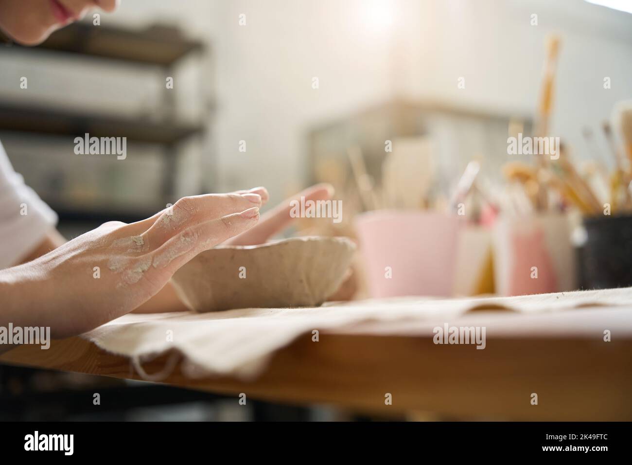 Lo studente scolpisce diligentemente i bordi della piastra di argilla con le dita Foto Stock