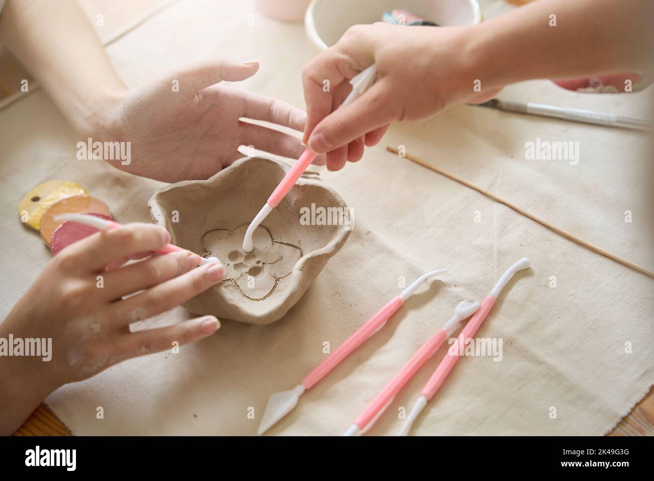 Gli artigiani applicano un modello a una piastra di argilla Foto Stock