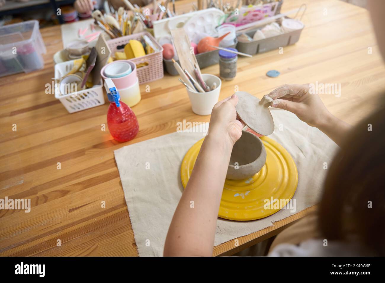Craftswoman al tavolo crea una pentola di argilla con coperchio Foto Stock