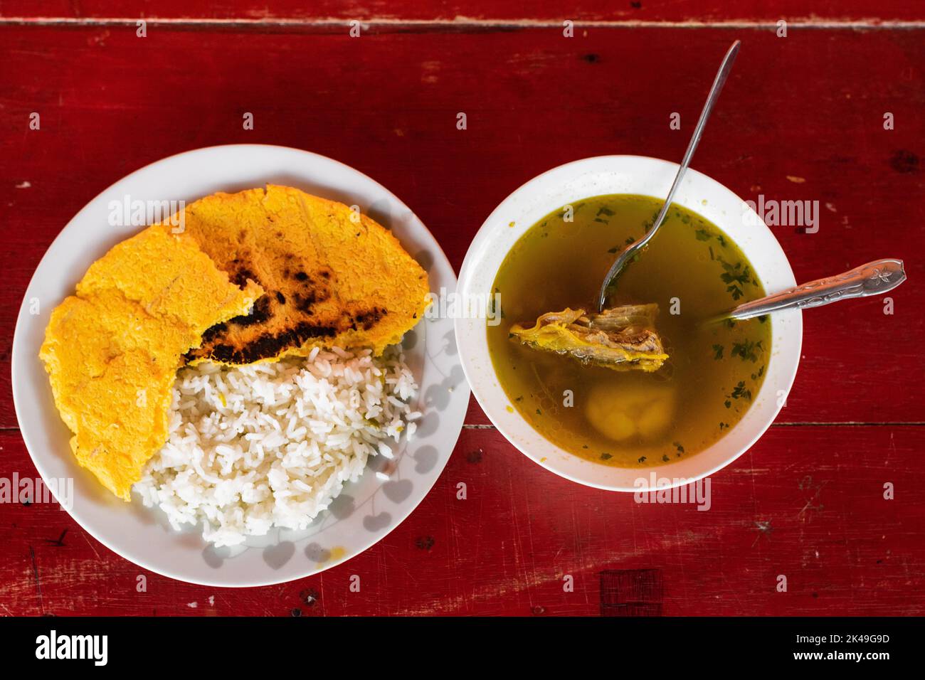 primo piano vista aerea di una colazione colombiana. brodo di manzo accompagnato da riso bianco e arepa gialla fatti a mano in una fattoria colombiana. piatto tipico del Foto Stock